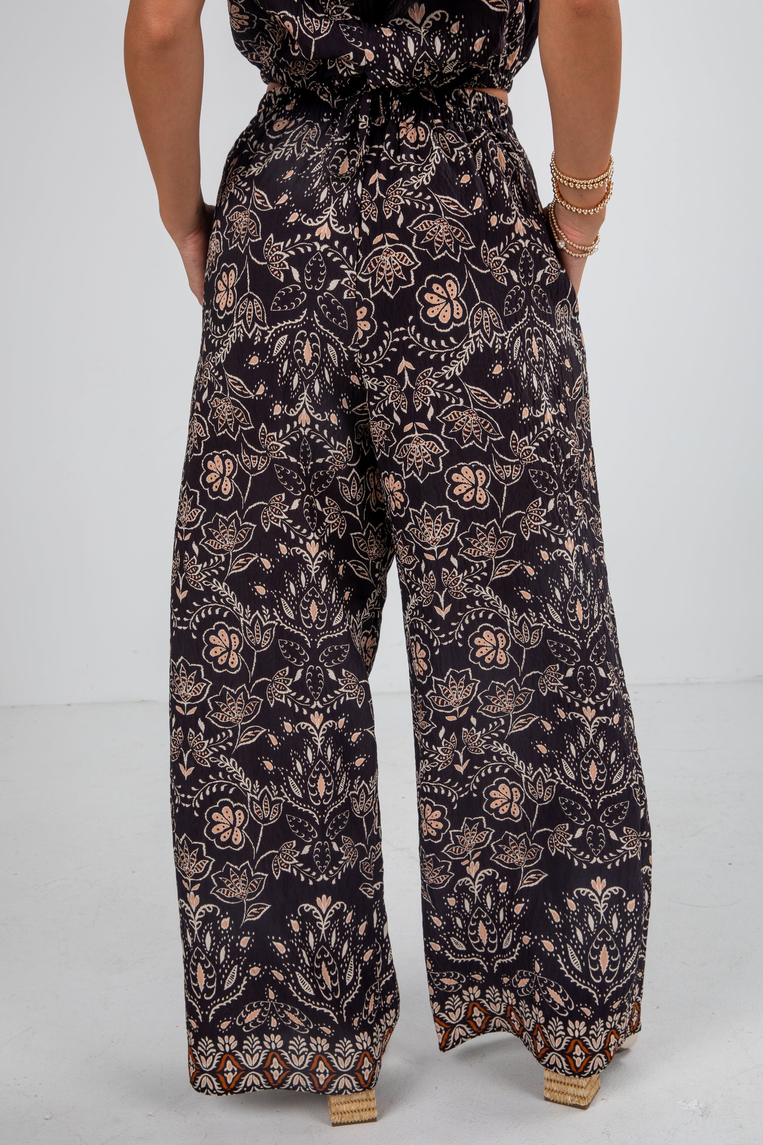 Person wearing a dark floral jumpsuit on a light gray background