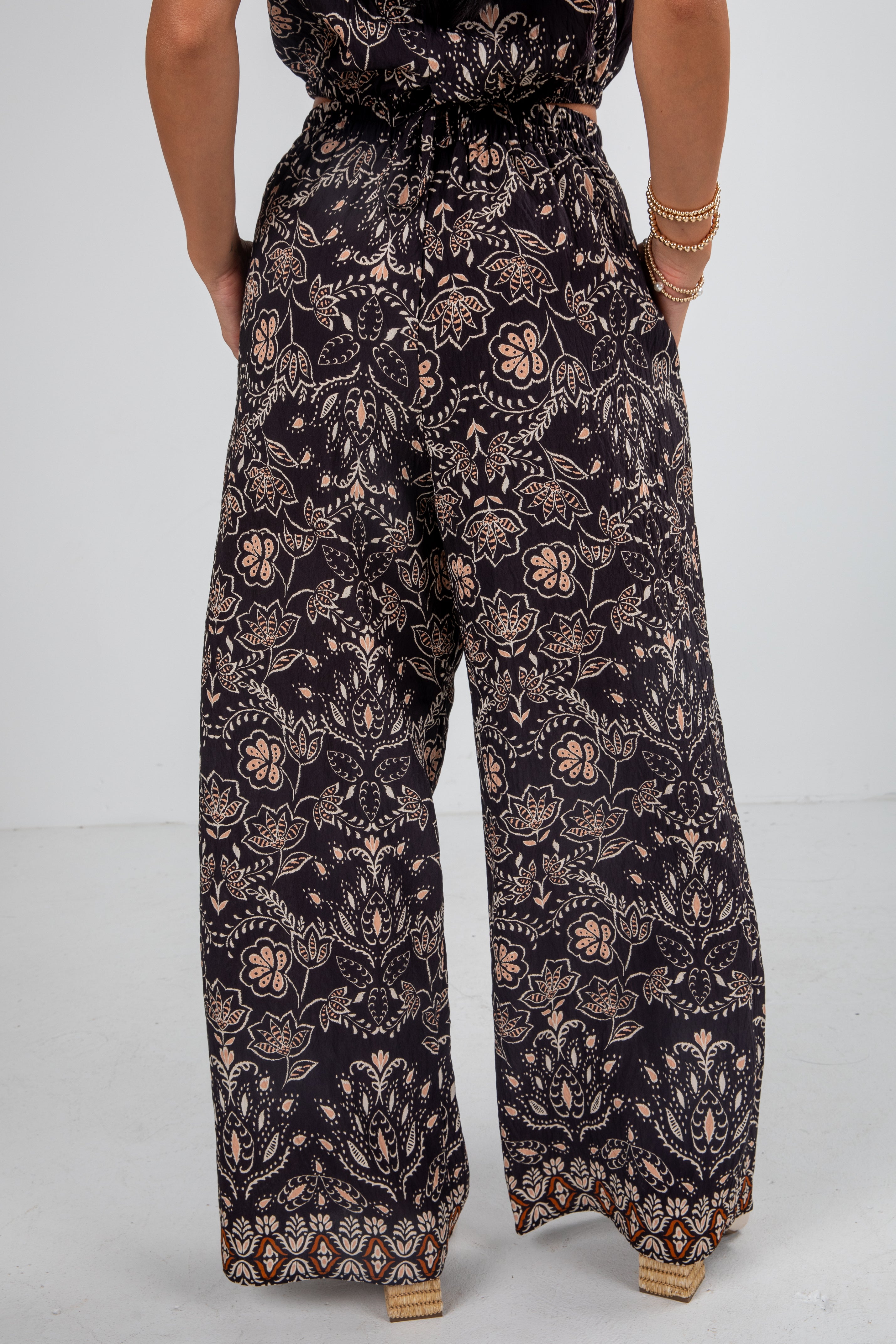 Person wearing a dark floral jumpsuit on a light gray background