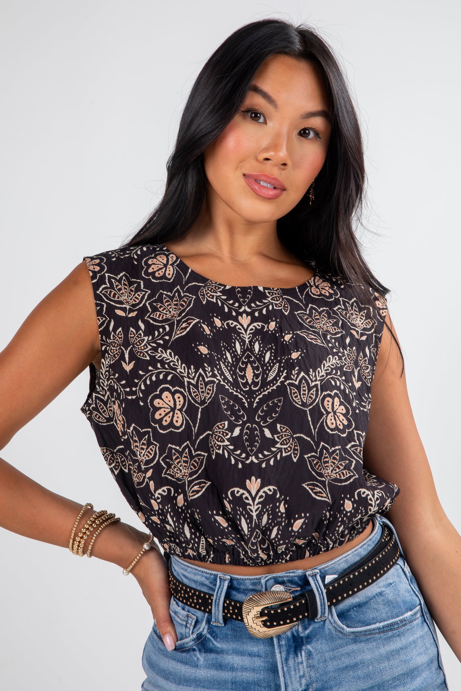 Woman wearing a patterned top and jeans against a white background