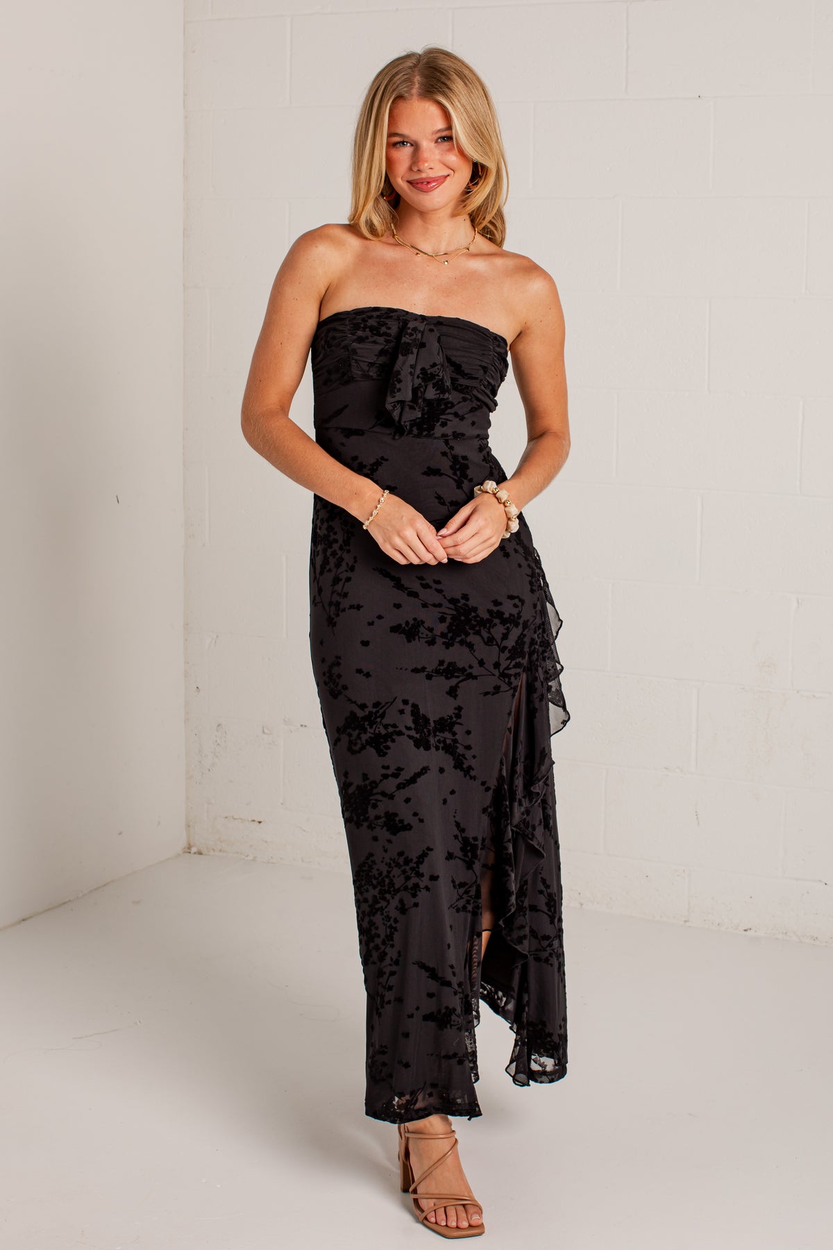 black midi dress features a tonal floral burnout design, delicate strapless fit, and a softly ruffled neckline