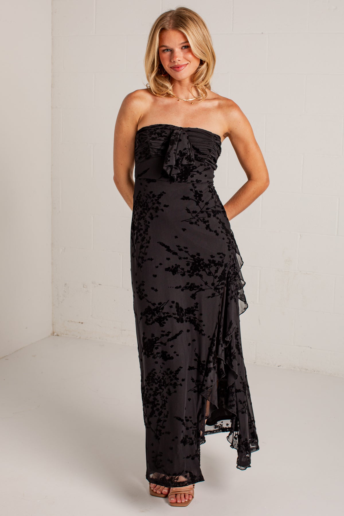 black midi dress features a tonal floral burnout design, delicate strapless fit, and a softly ruffled neckline