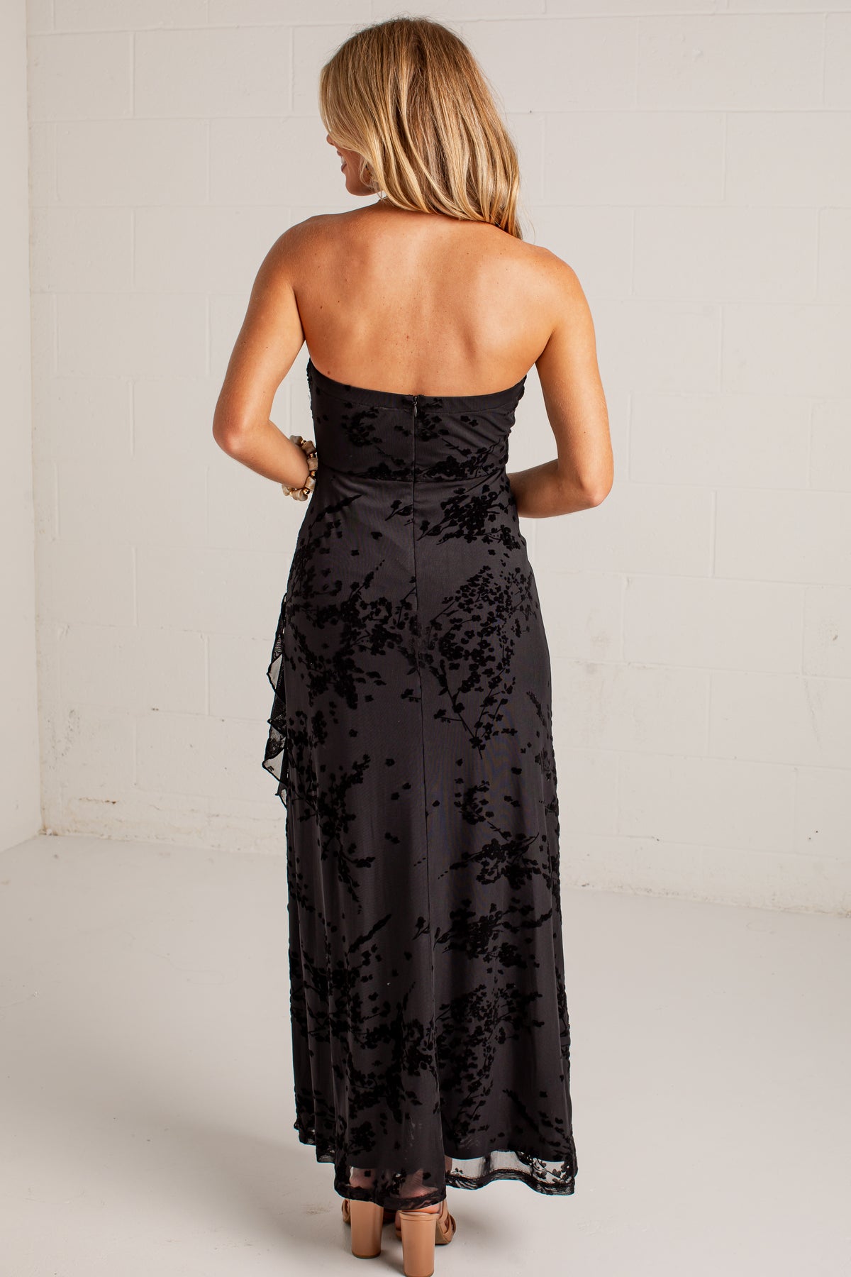 black midi dress features a tonal floral burnout design, delicate strapless fit, and a softly ruffled neckline