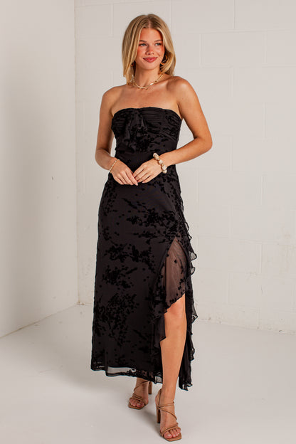 black midi dress features a tonal floral burnout design, delicate strapless fit, and a softly ruffled neckline