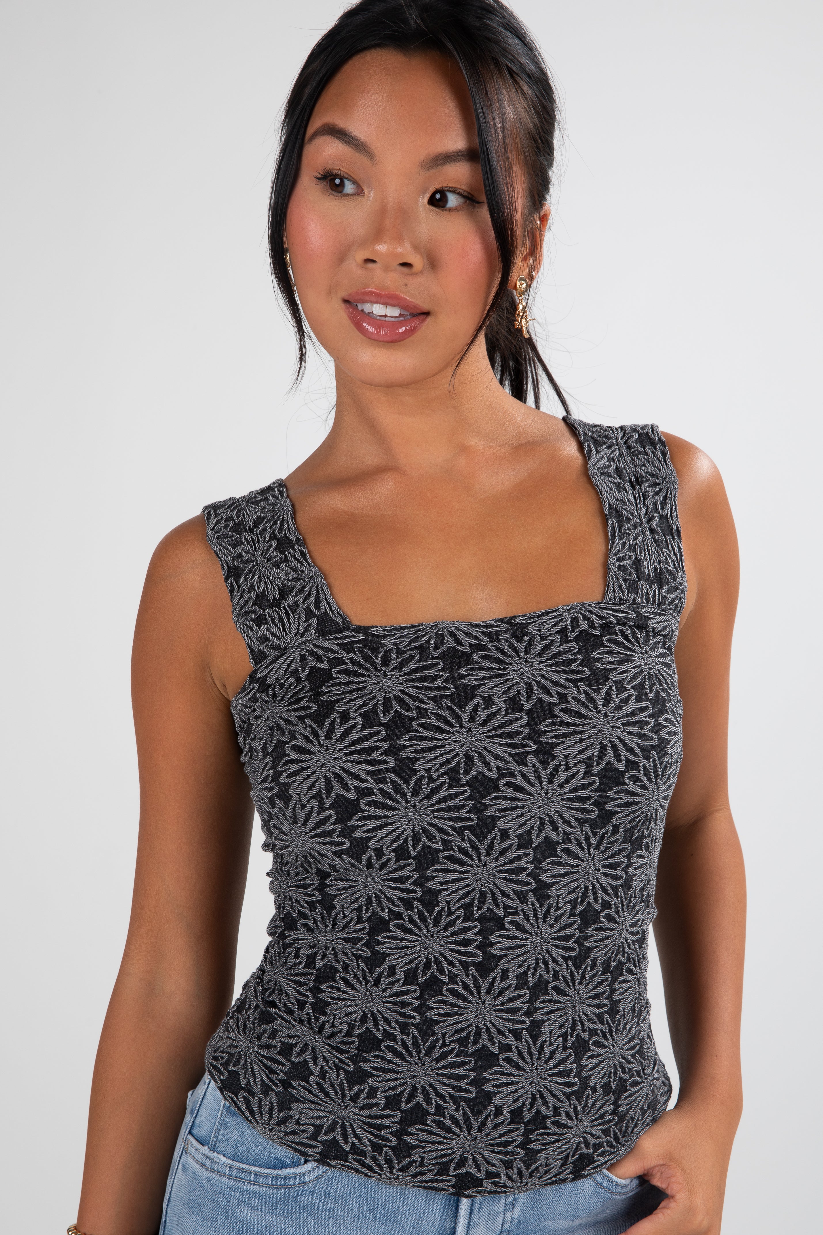 Woman wearing a black floral patterned tank top against a white background