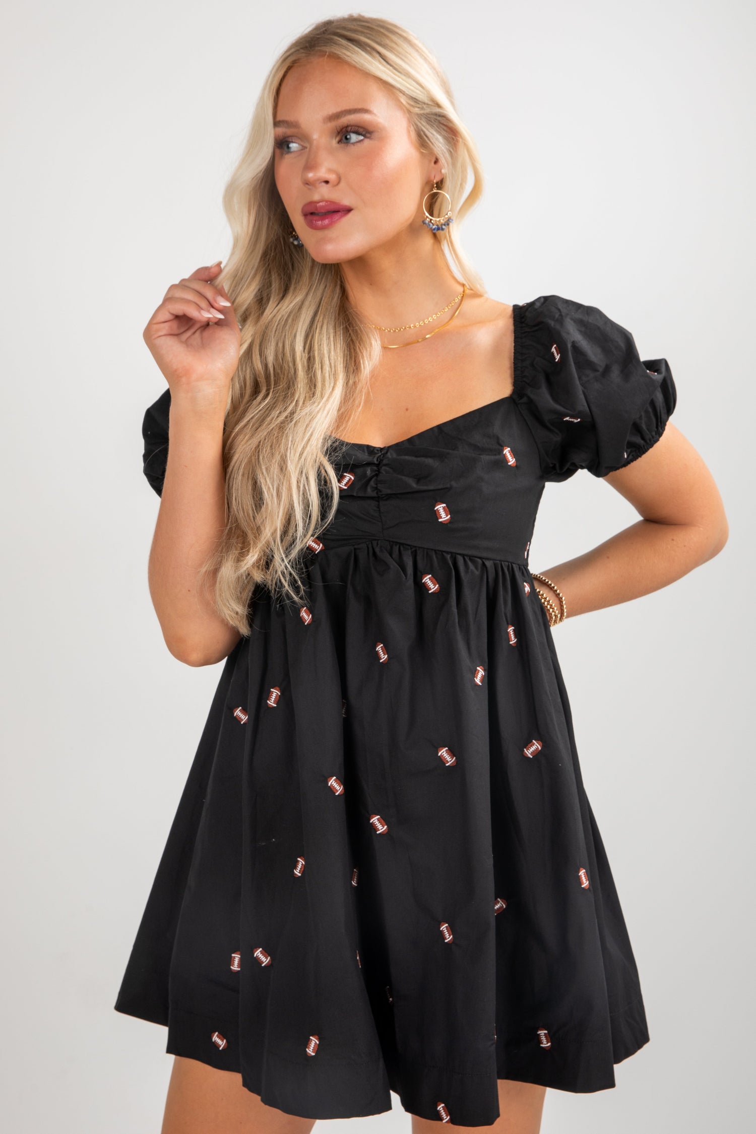 Woman wearing a black dress with pink details against a plain background