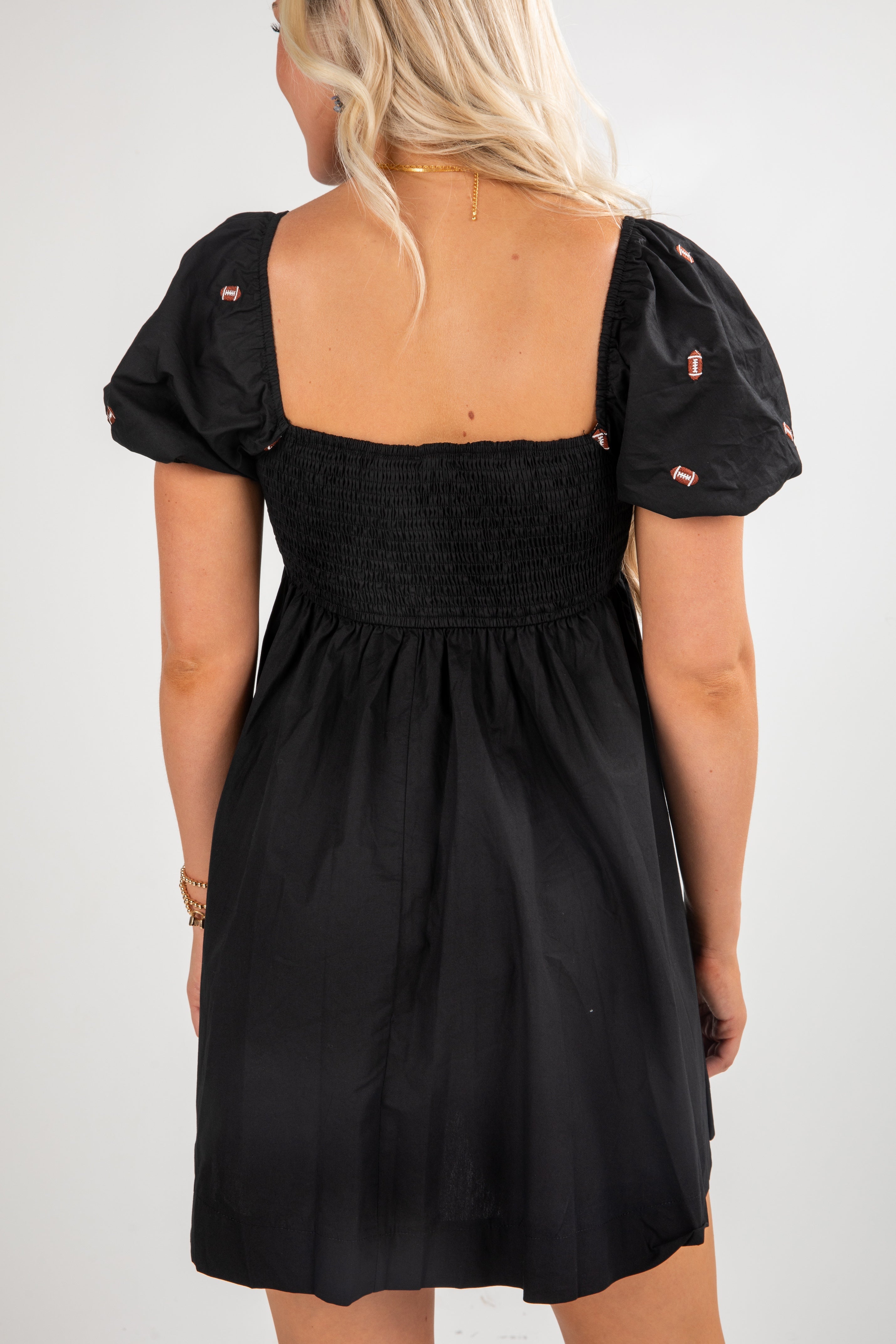 Black dress with puff sleeves worn by a person on a white background