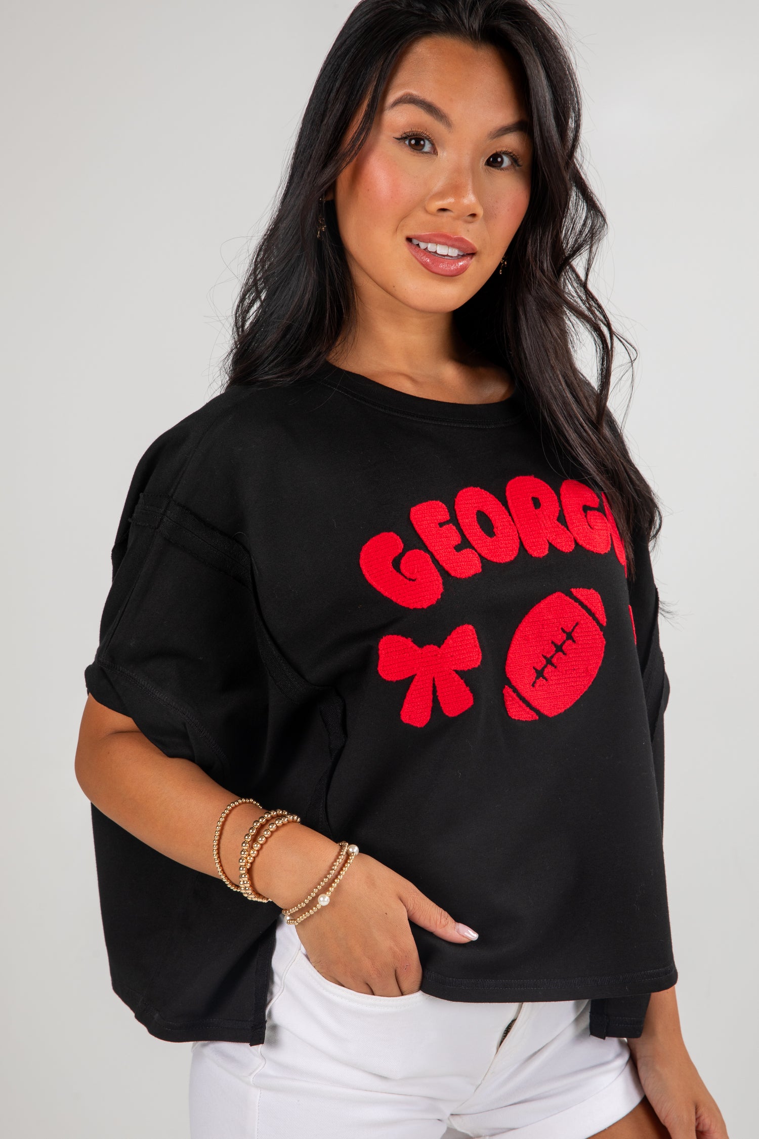 Woman wearing a black shirt with red text and graphics on a plain background