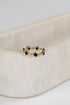 Gold ring with black stones on a beige fabric background