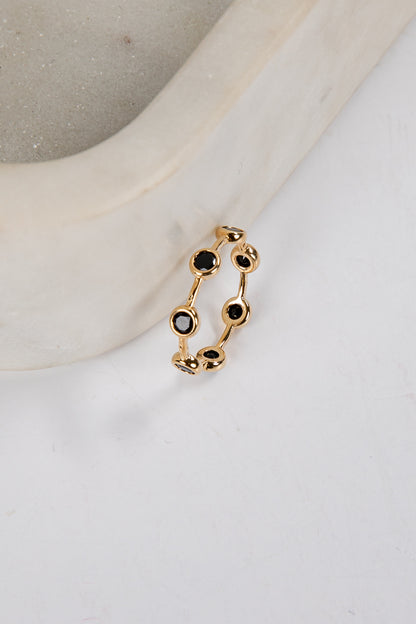 Gold ring with black gemstones on a white surface