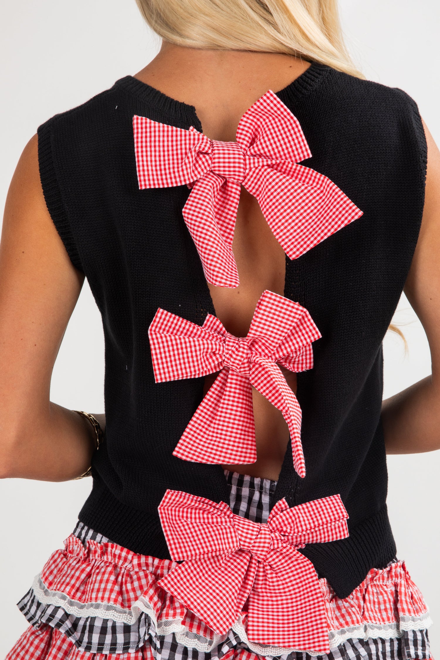 Black sleeveless top with pink checkered bows on a plain background