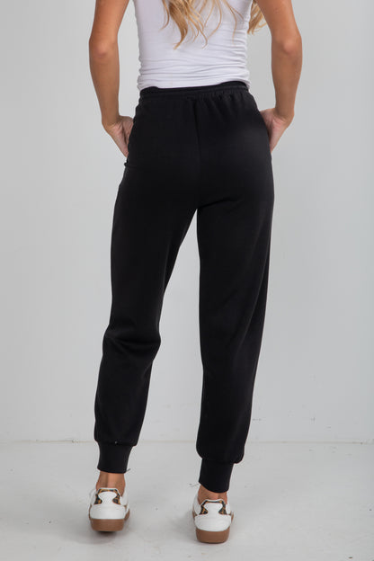 Person wearing black sweatpants on a plain background