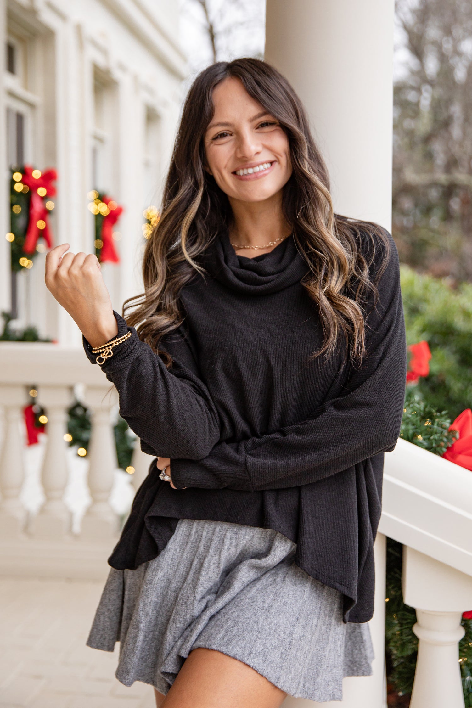 Woman wearing a black sweater and gray skirt on a decorated porch