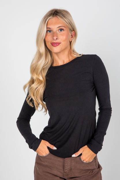 Woman wearing a black long-sleeve top against a plain background