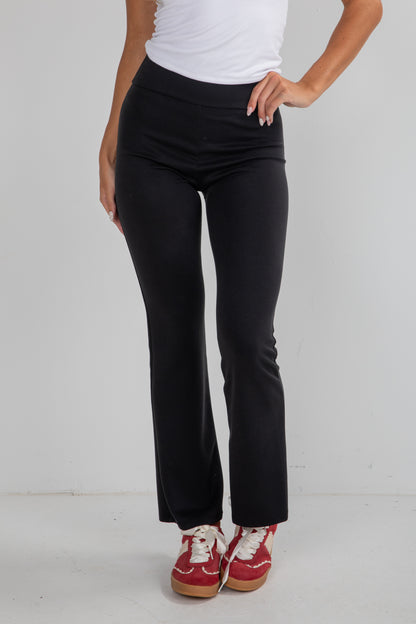 Person wearing black pants and red shoes on a white background