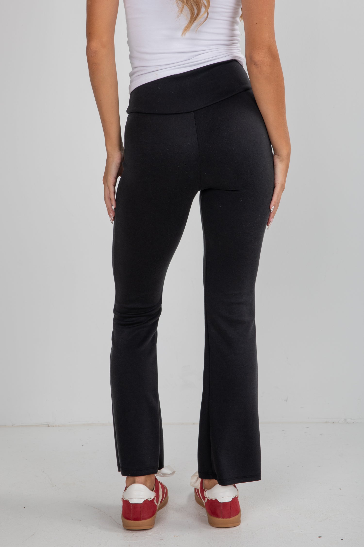 Person wearing black pants and red shoes on a white background