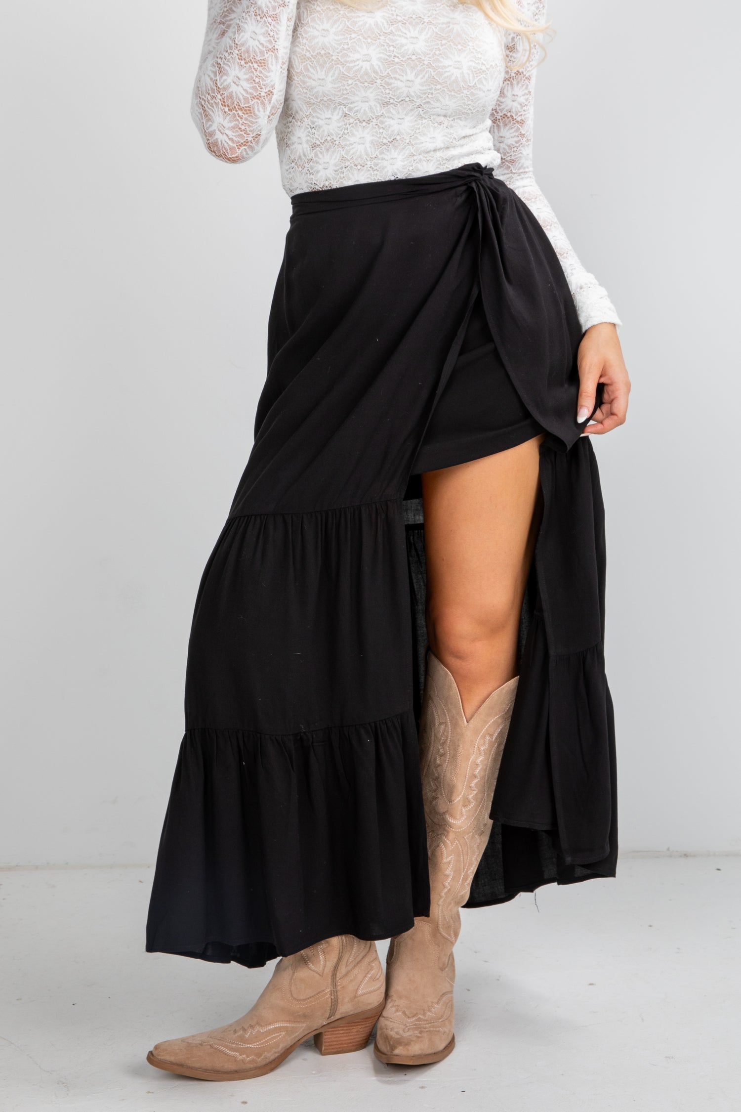 Person wearing a black tiered skirt with beige boots on a white background
