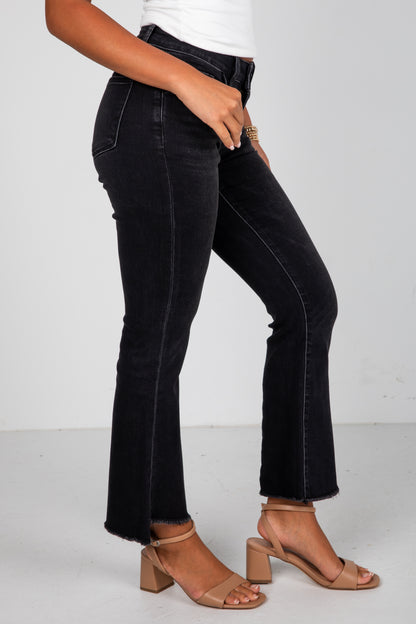 Person wearing black jeans and brown sandals on a white background