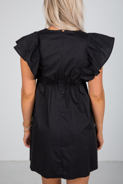 Black dress with ruffled shoulders on a plain background