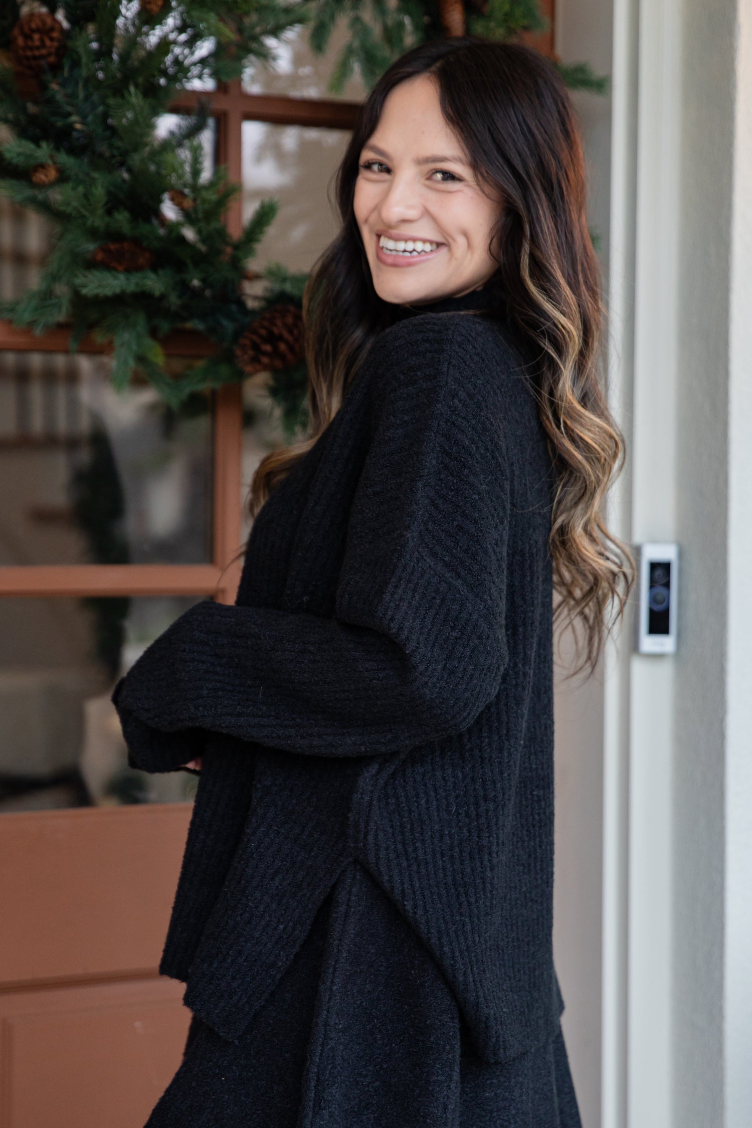 Woman in a dark sweater standing indoors with a decorative background