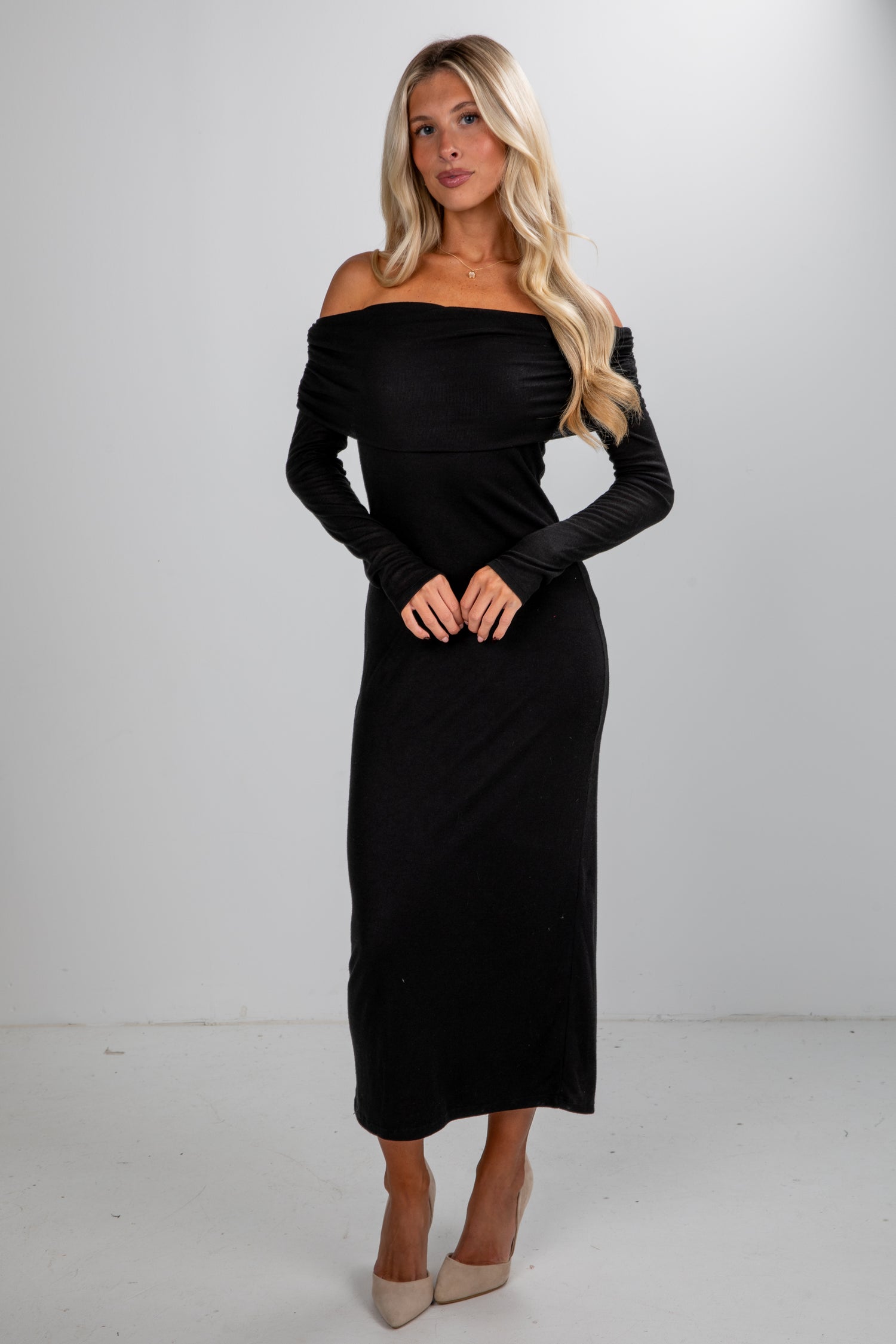 Woman wearing a black off-shoulder dress against a white background