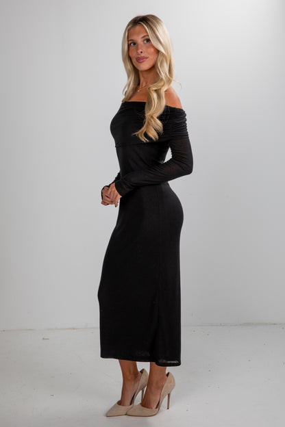 Woman wearing a black off-shoulder dress against a white background