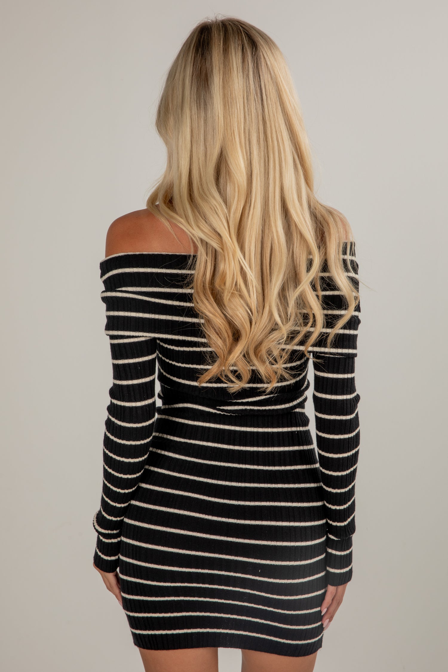 Black and white striped dress worn by a person with long blonde hair on a plain background
