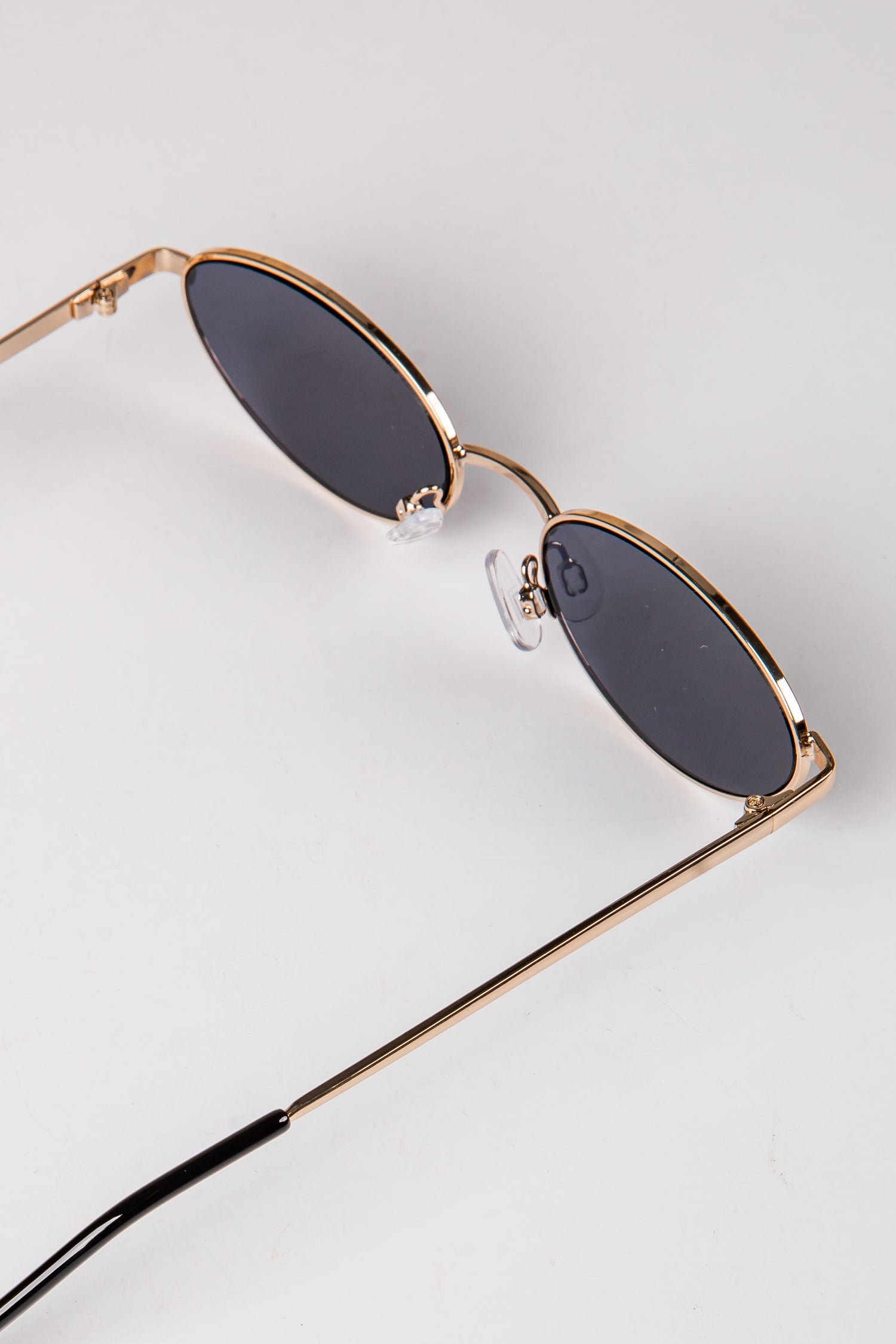 Sunglasses with gold frame and dark lenses on a light gray background