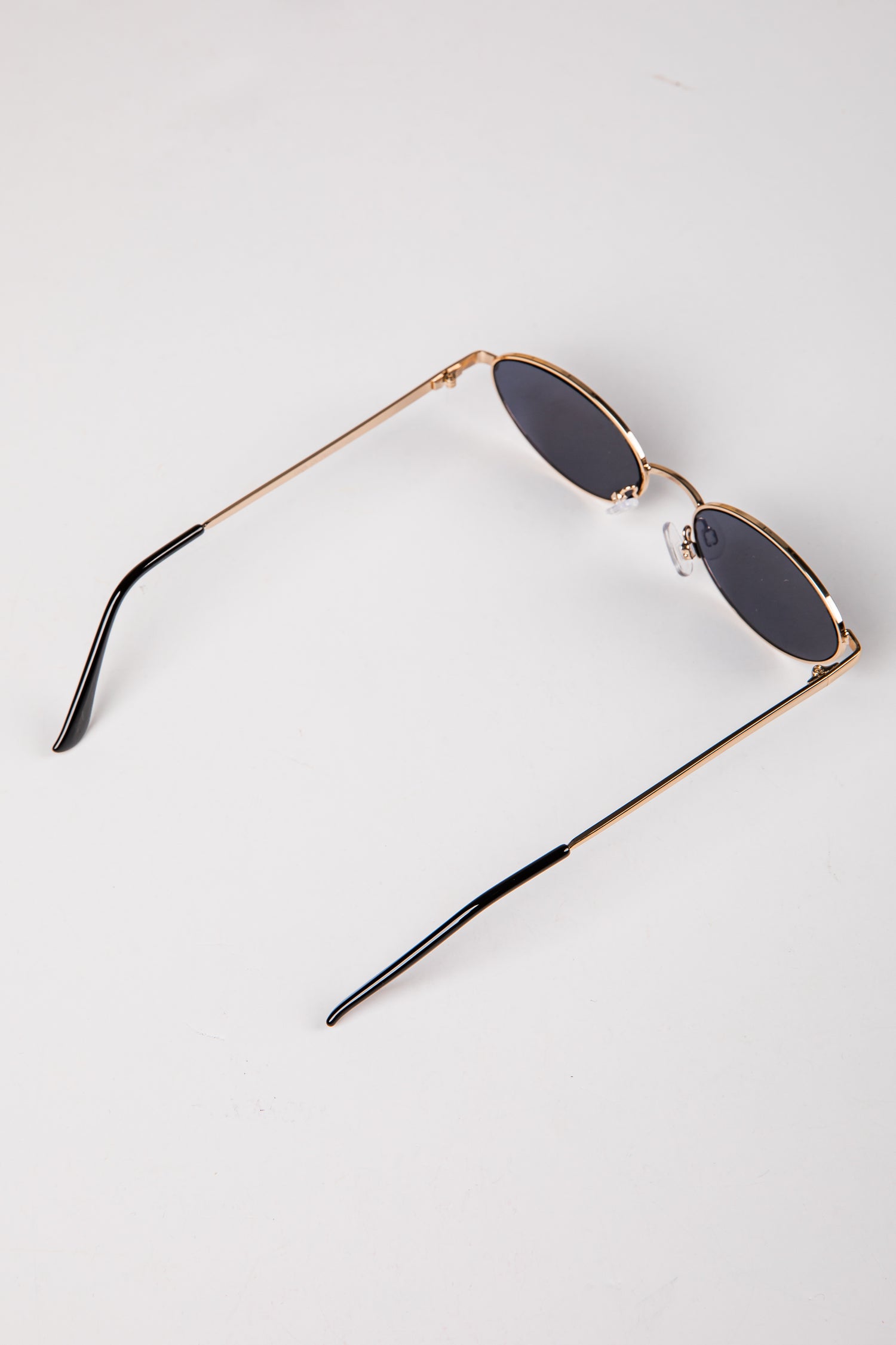 Sunglasses with gold frame and dark lenses on a white background
