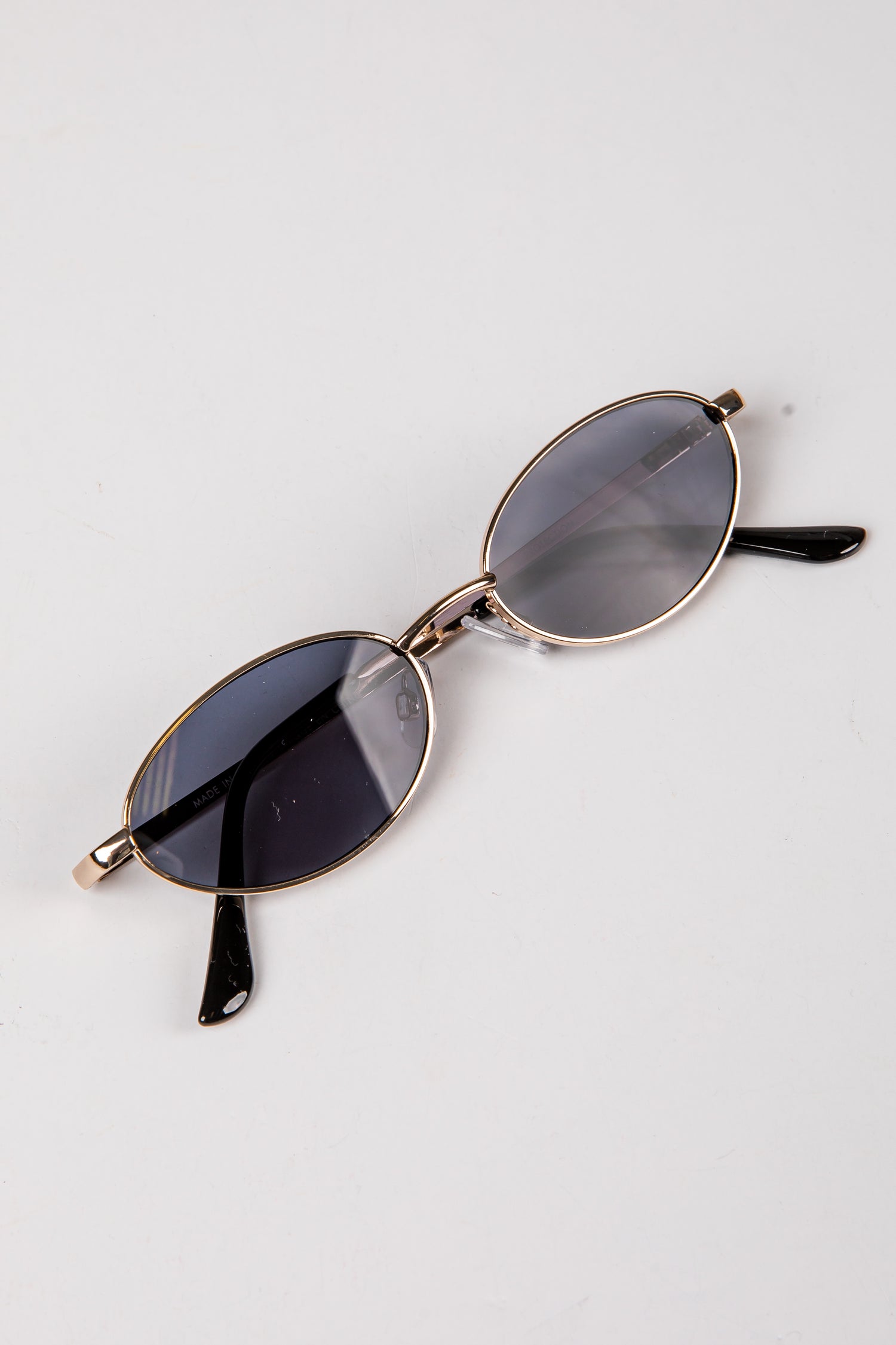 Sunglasses with gold frame and dark lenses on a white background