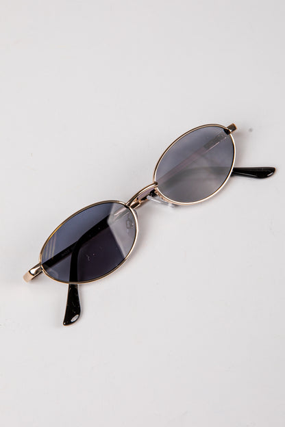 Sunglasses with gold frame and dark lenses on a white background