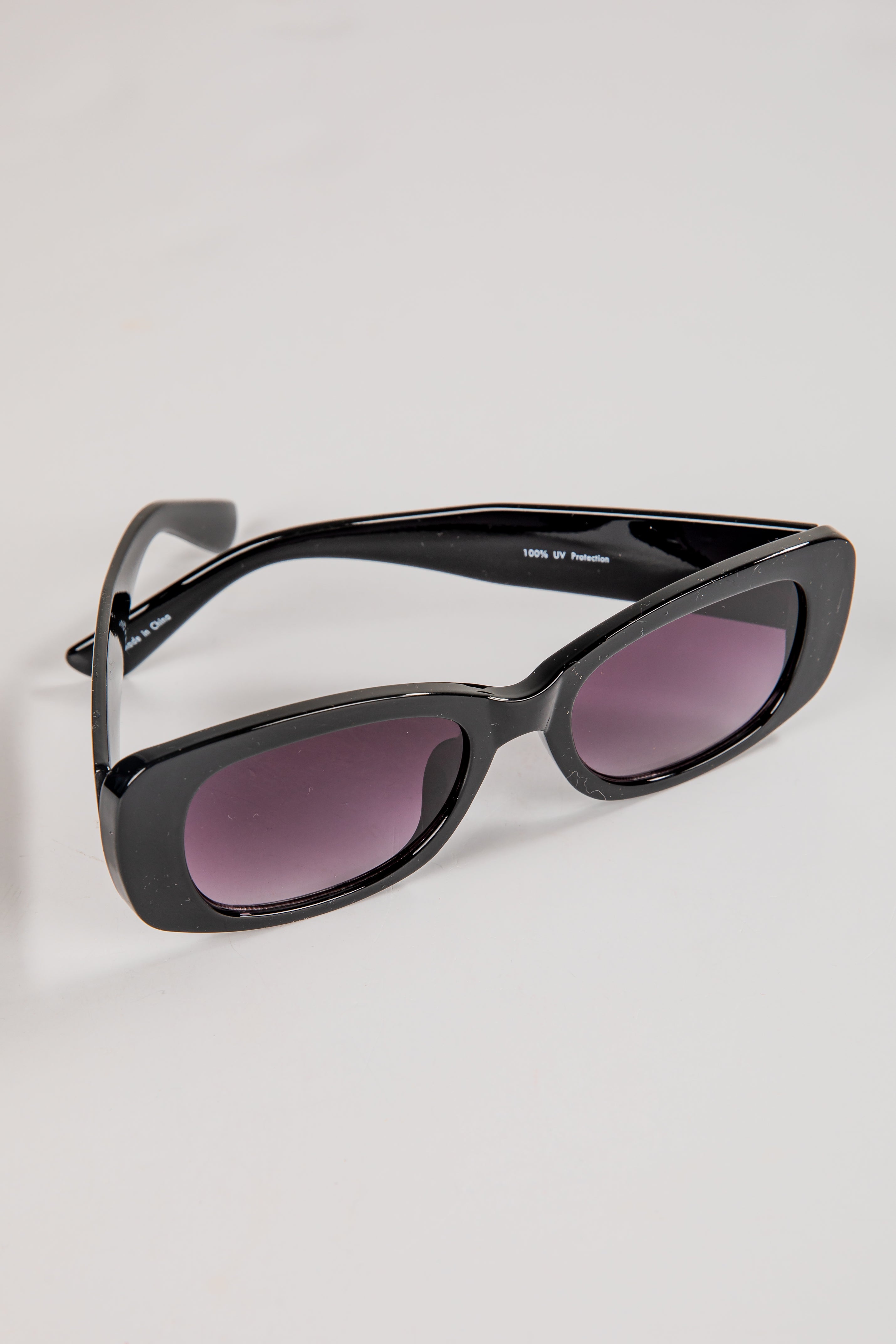 Black sunglasses with purple lenses on a light gray background