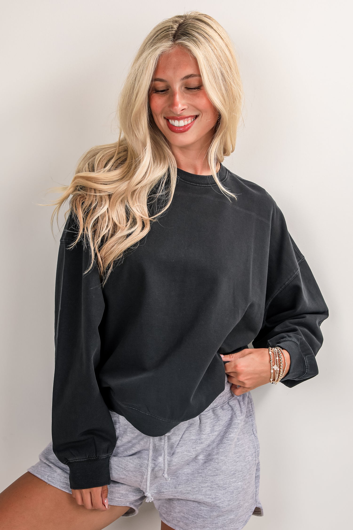 Woman wearing a black sweatshirt and gray shorts against a plain background