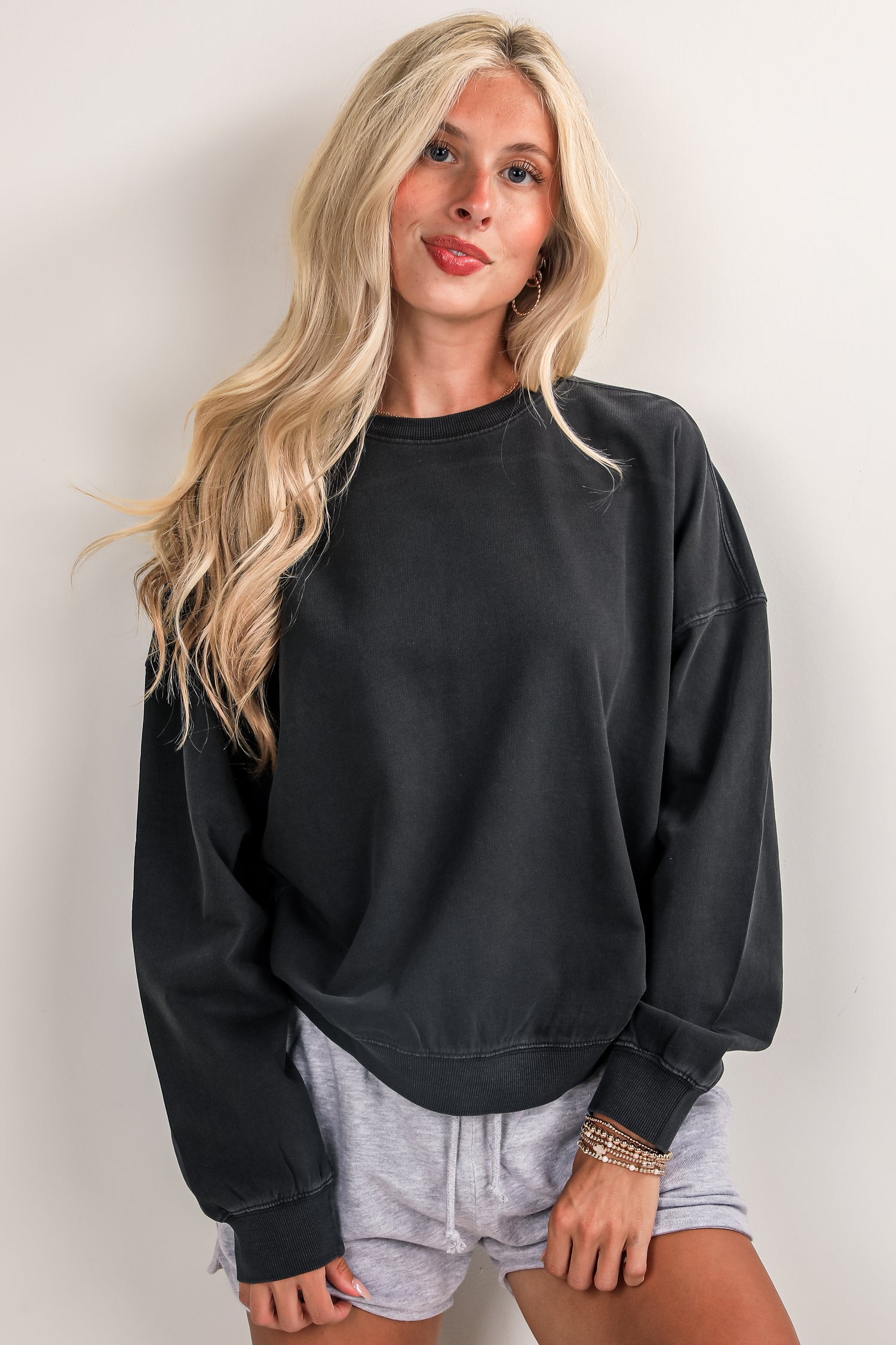 Woman wearing a black sweatshirt and gray shorts against a plain background