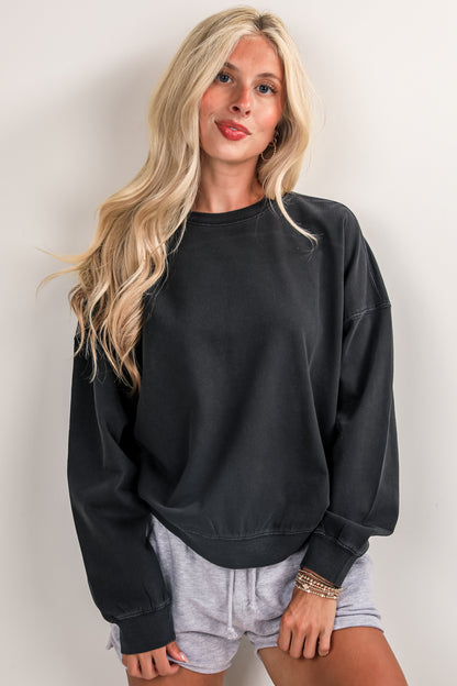 Woman wearing a black sweatshirt and gray shorts against a plain background