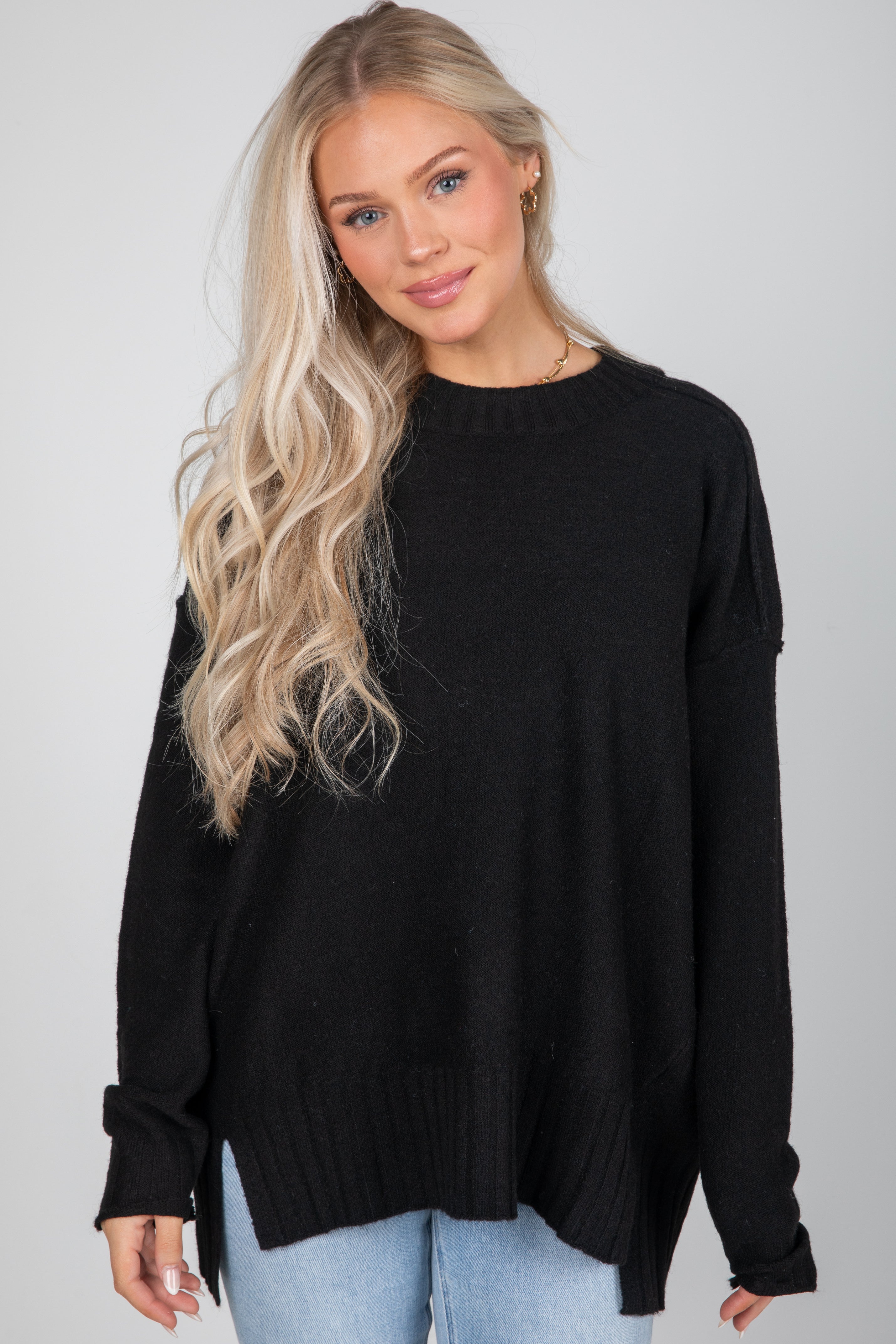 Woman wearing a black sweater against a plain background