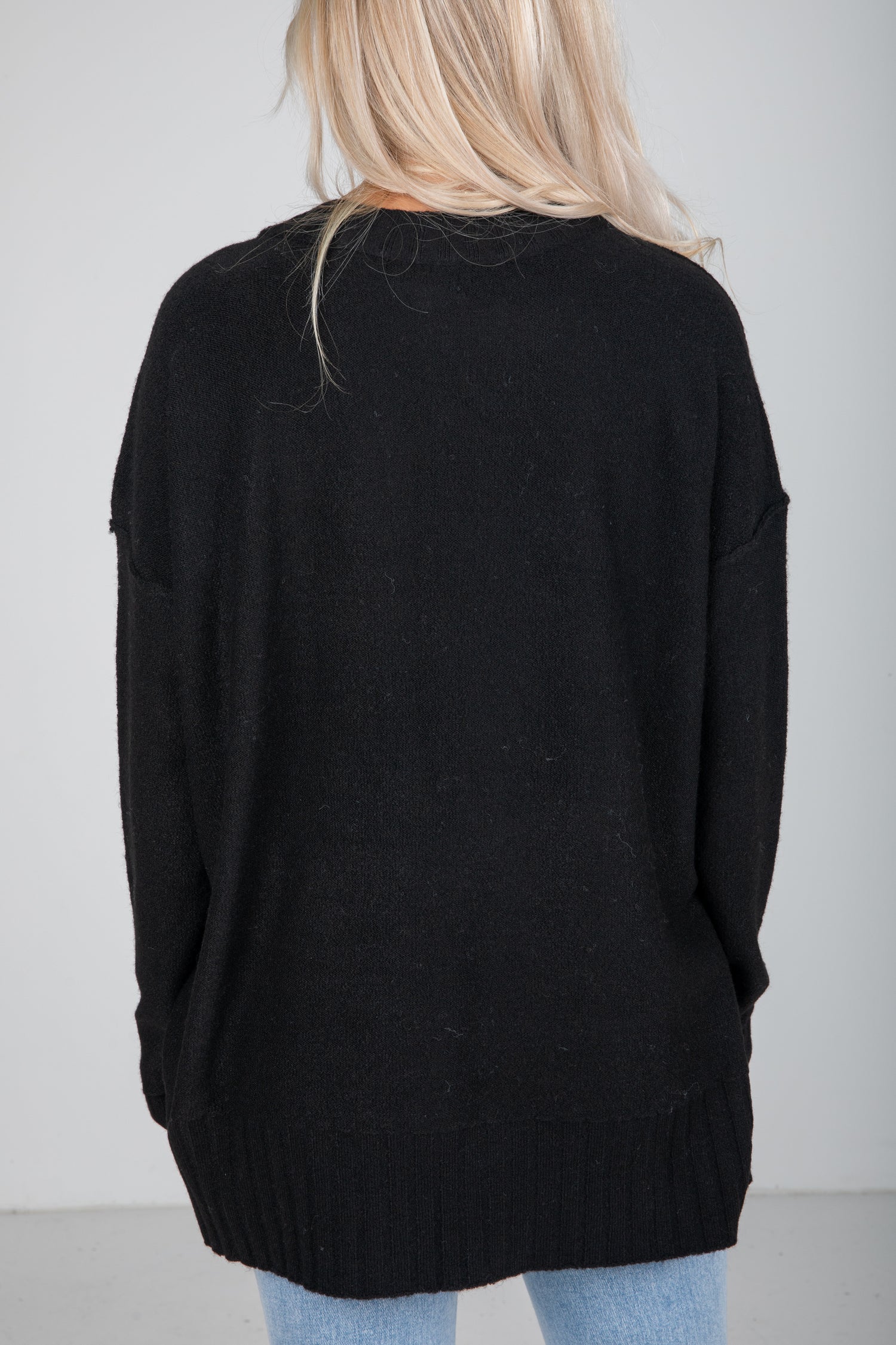 Person wearing a black sweater with a plain background