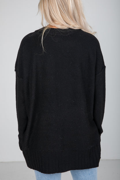 Person wearing a black sweater with a plain background