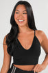 Woman wearing a black tank top against a plain background