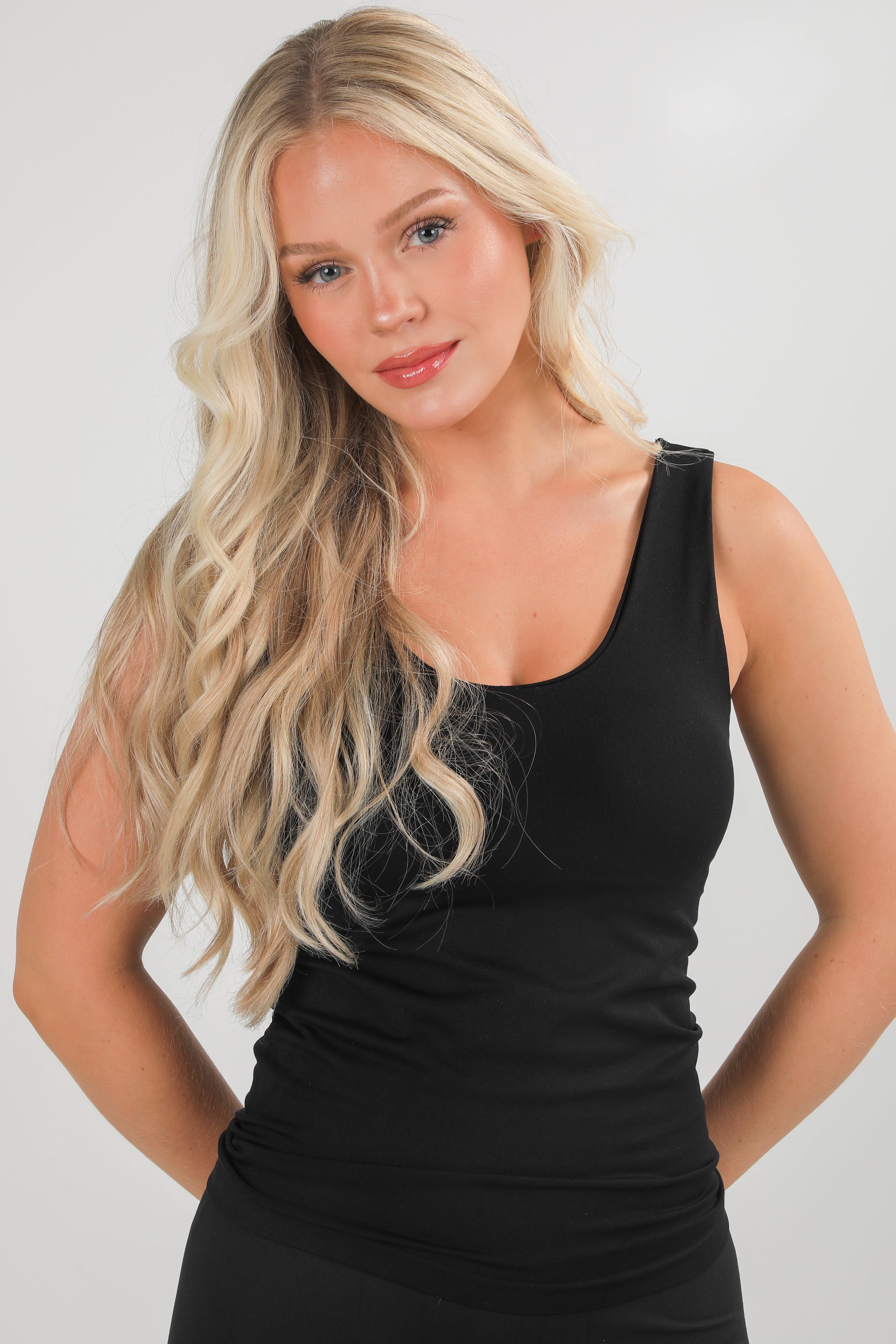 Woman wearing a black sleeveless top against a plain background