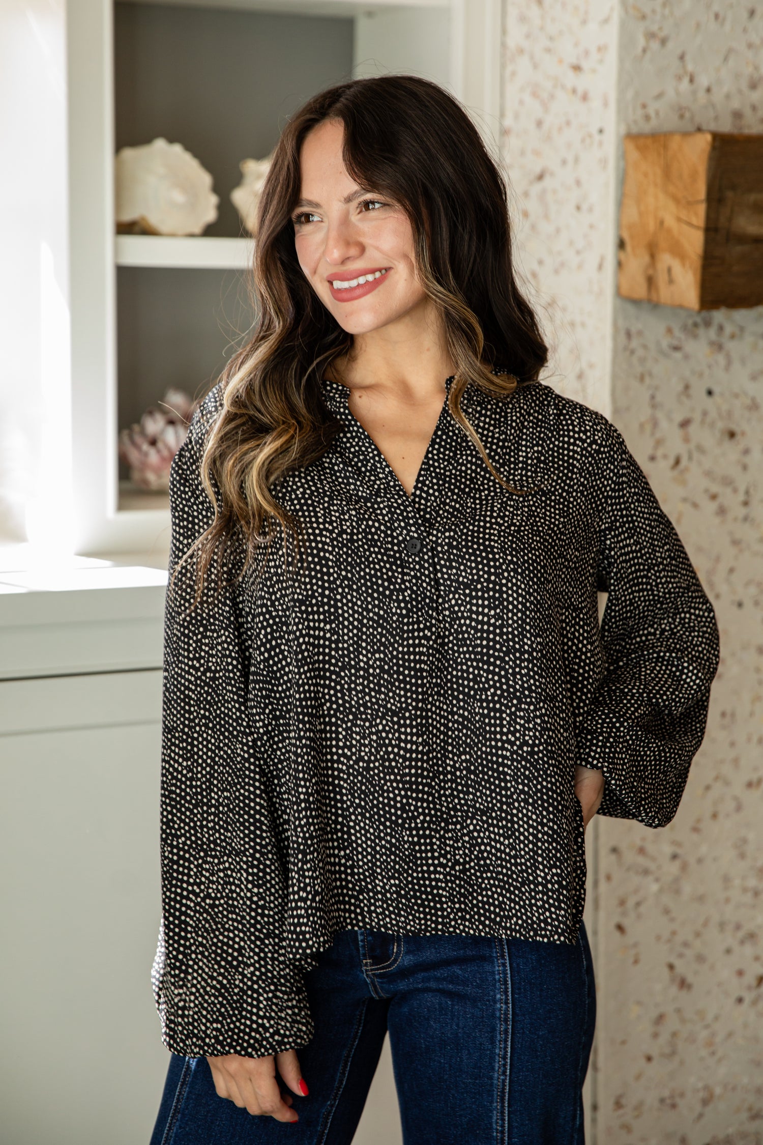 Woman wearing a black and white patterned blouse in an indoor setting