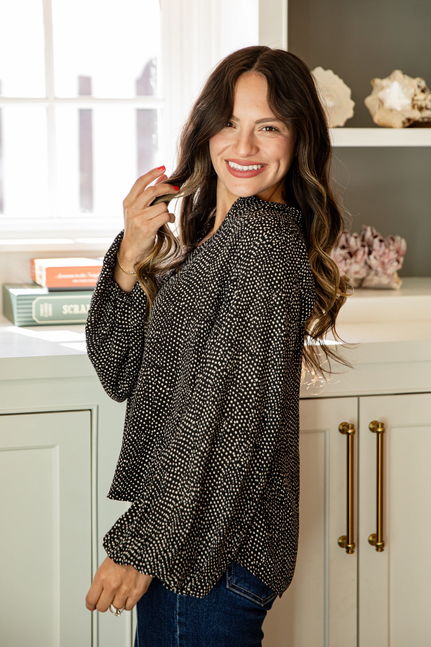 Woman wearing a black patterned blouse in a kitchen setting