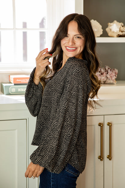 Woman wearing a black patterned blouse in a kitchen setting