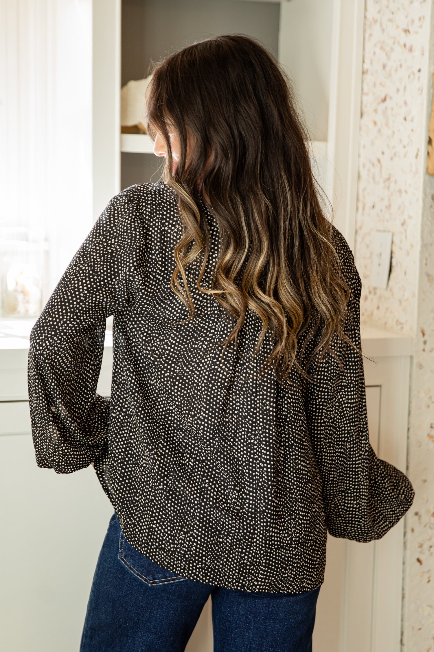 Woman wearing a patterned blouse in a bathroom setting