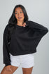 Woman wearing a black oversized sweater and white shorts on a gray background