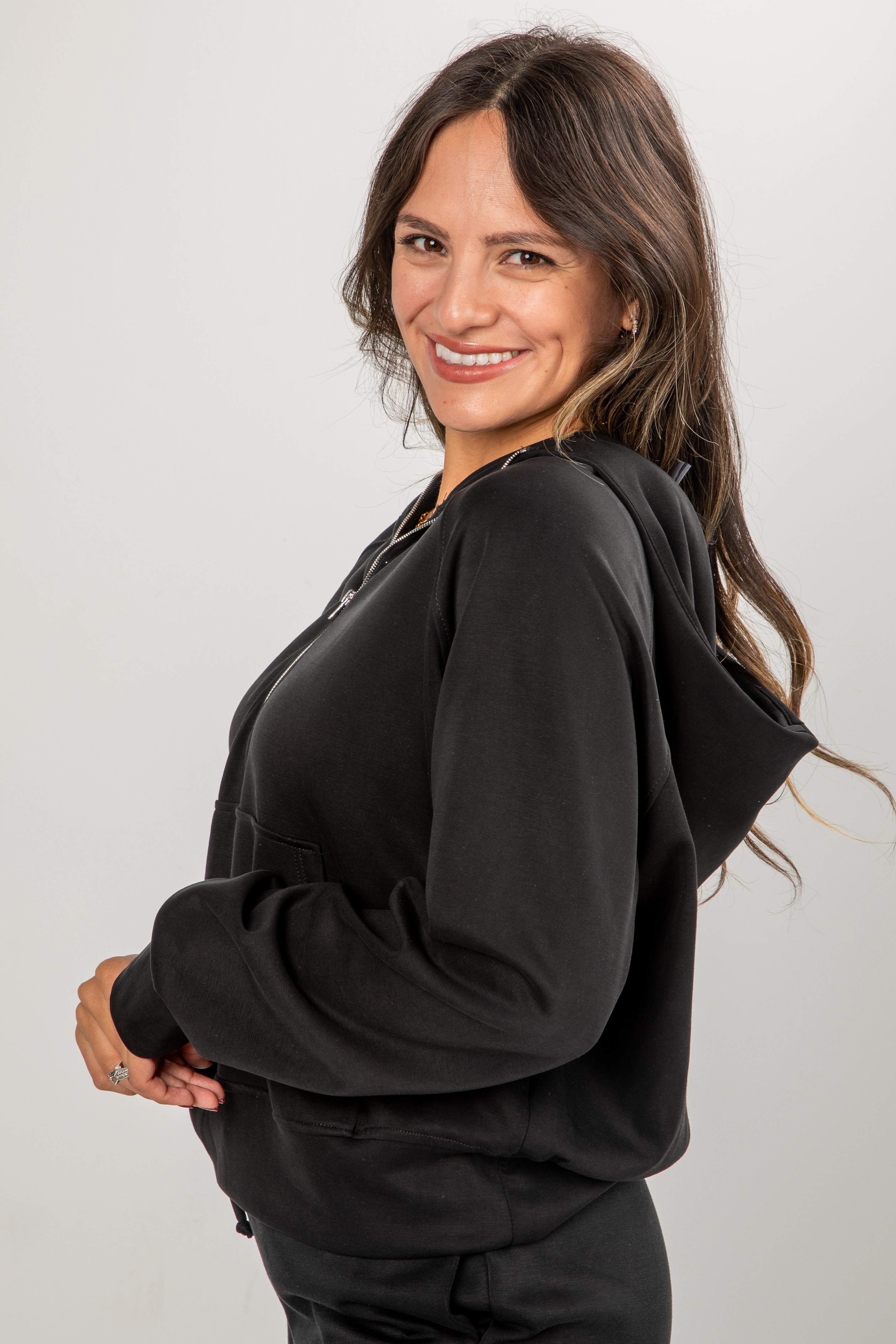 Woman wearing a black hoodie against a plain background
