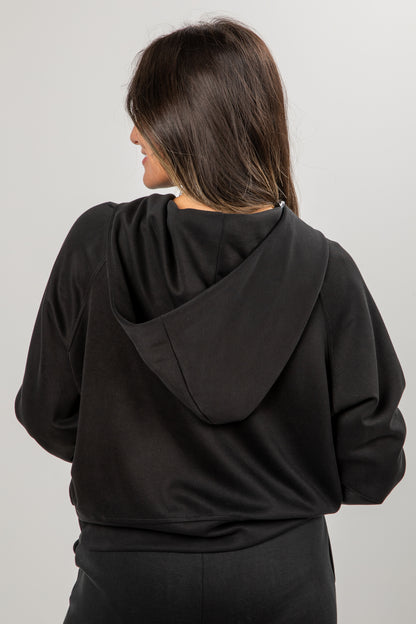 Person wearing a black hoodie from behind on a plain background