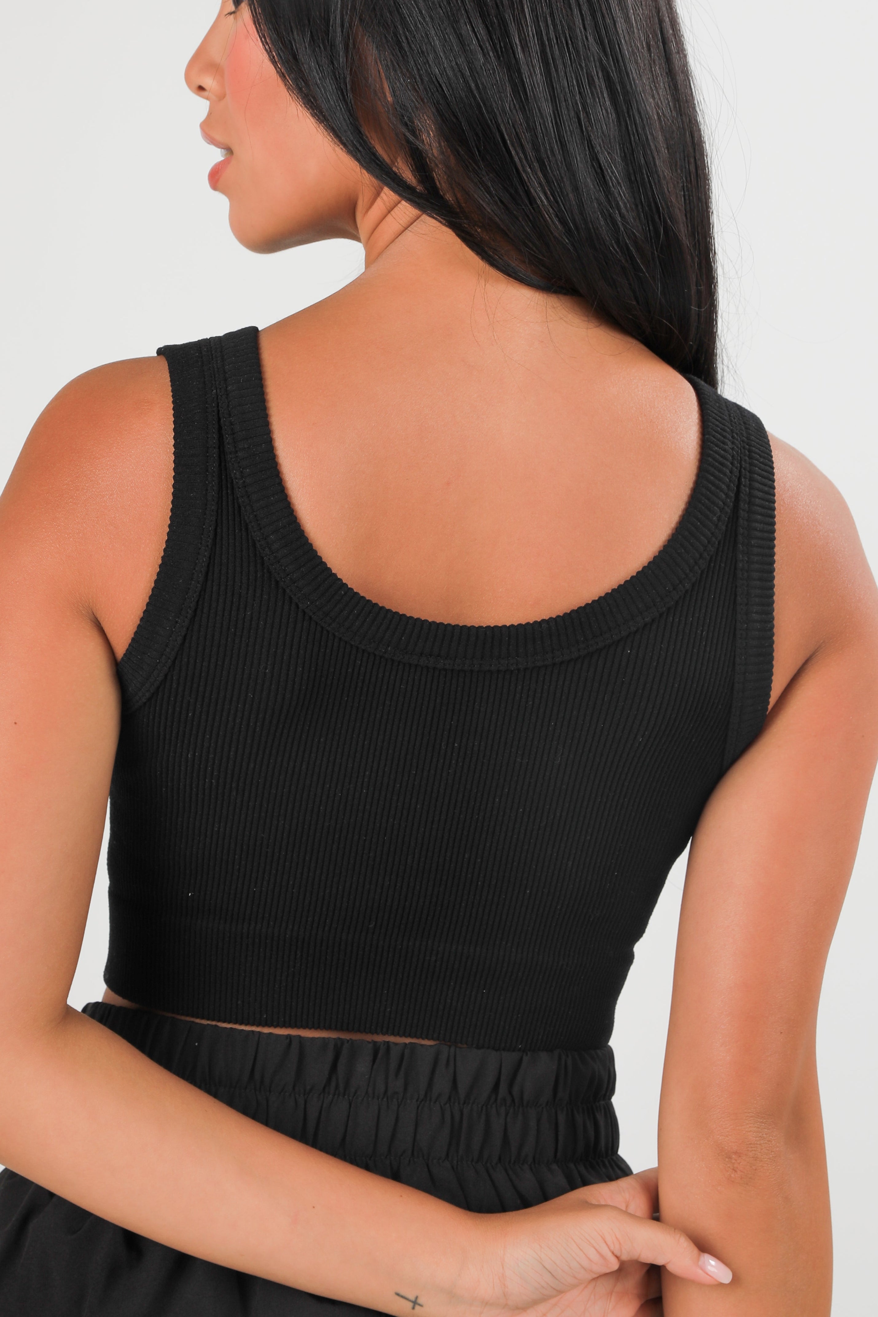 Person wearing a black sleeveless top against a white background