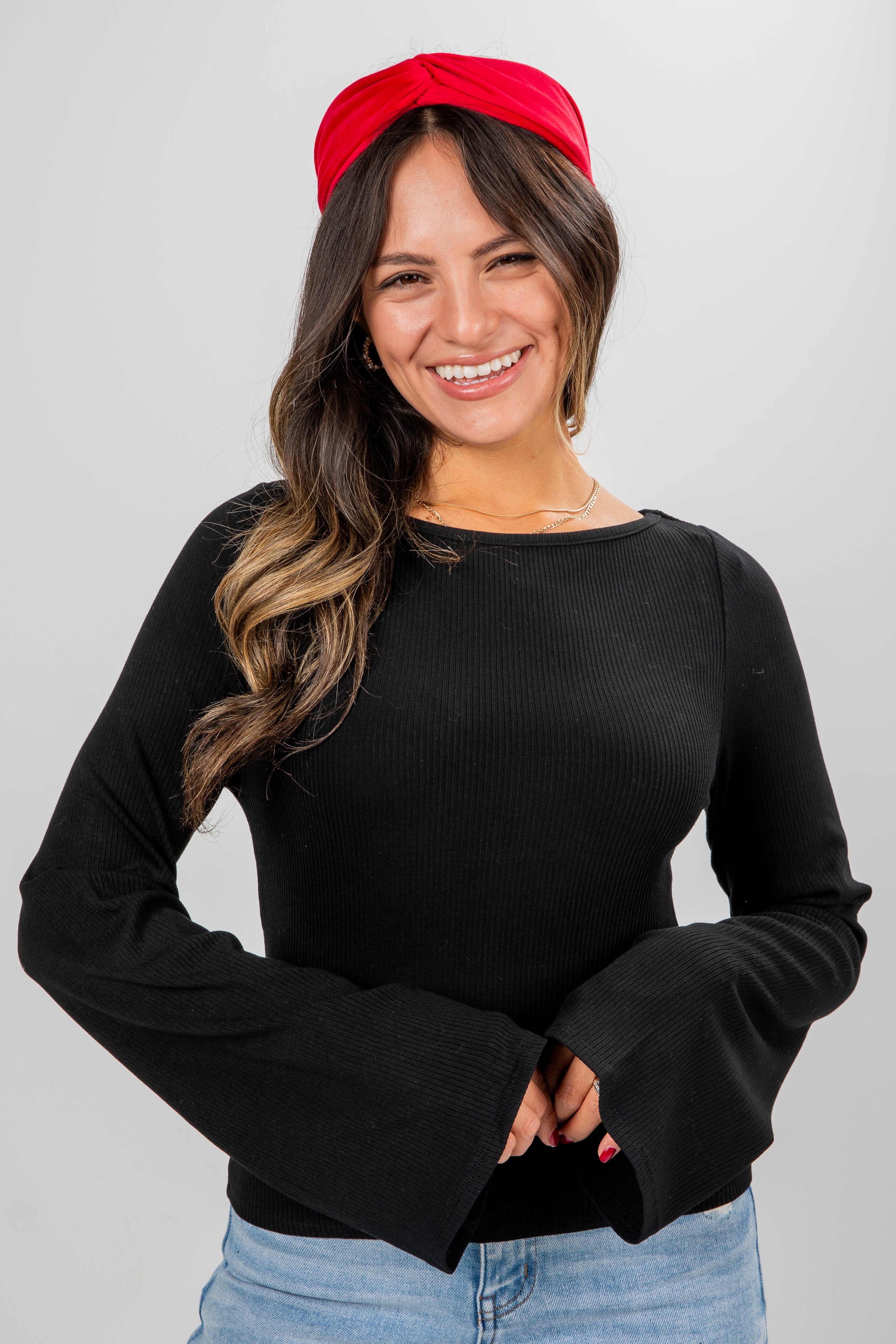 Woman wearing a black long-sleeve top and red headband on a gray background
