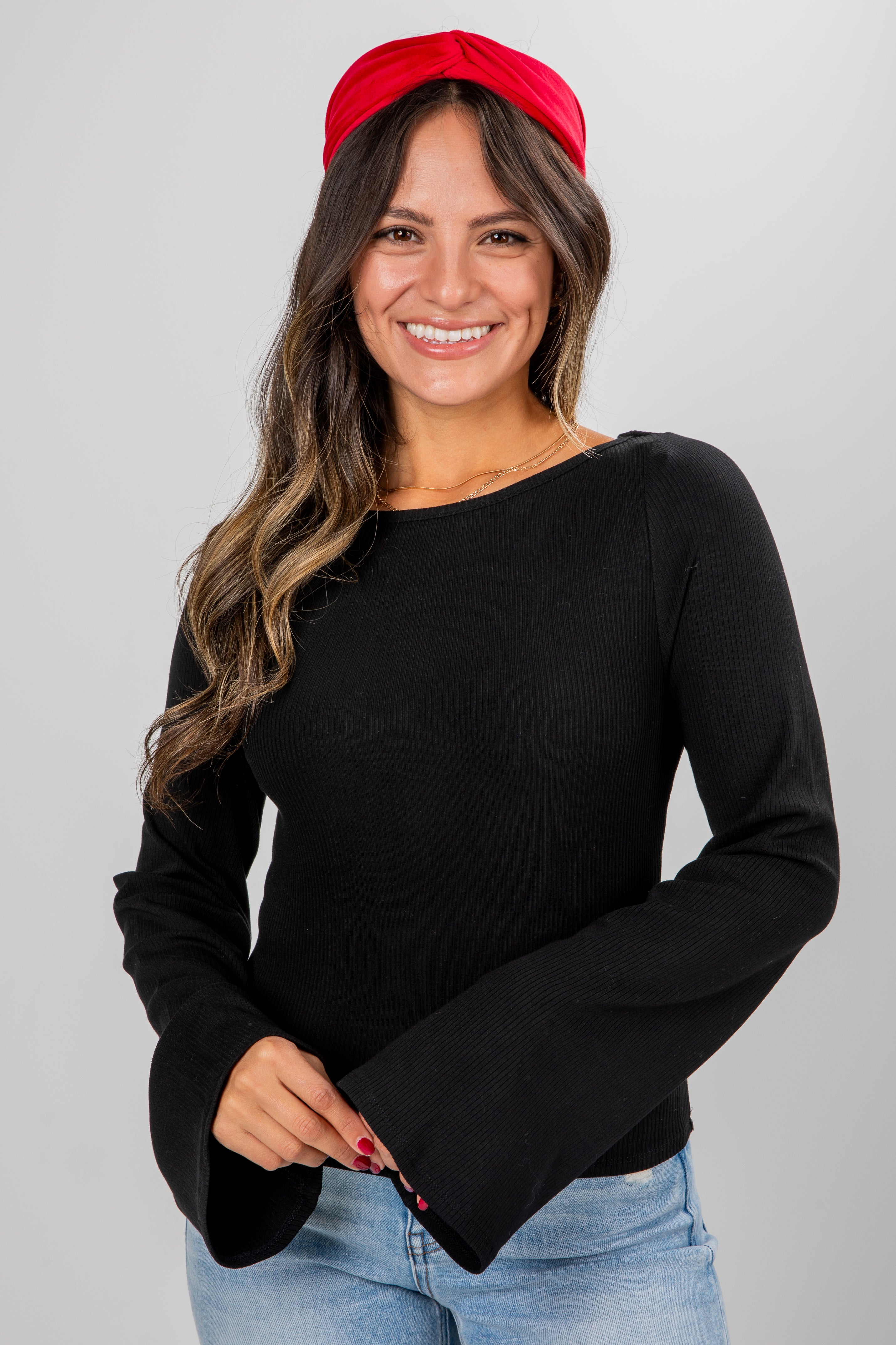 Woman wearing a black long-sleeve top and red headband on a gray background