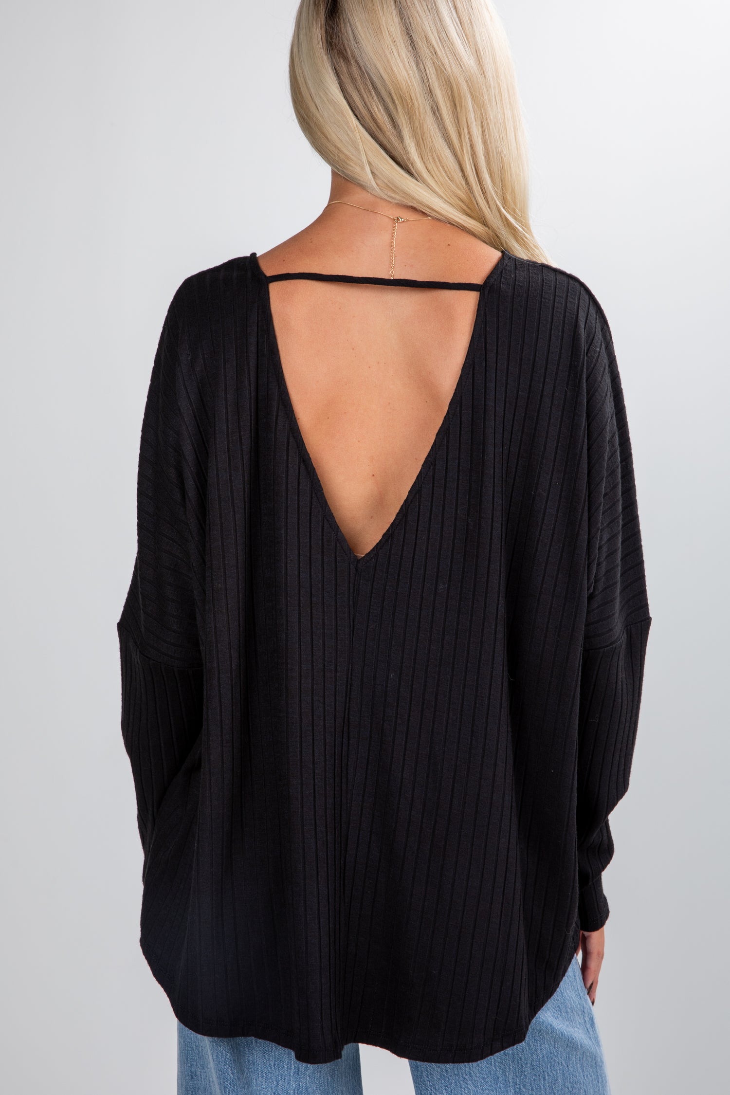 Black open-back top worn by a person on a plain background